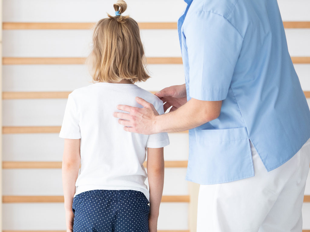 a chiropractor checking the young kid's back
